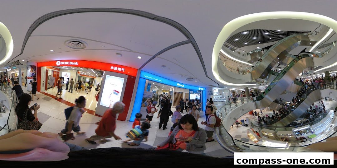 A busy shopping mall interior with OCBC Bank and POSB branches visible, and escalators filled with people.