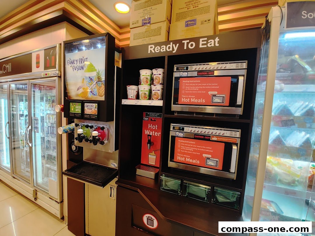 A 7-Eleven store section featuring a drink dispenser, microwaves for hot meals, and refrigerated drinks.