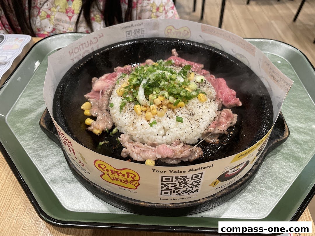 A sizzling hot plate of rice with beef and corn, garnished with green onions.
