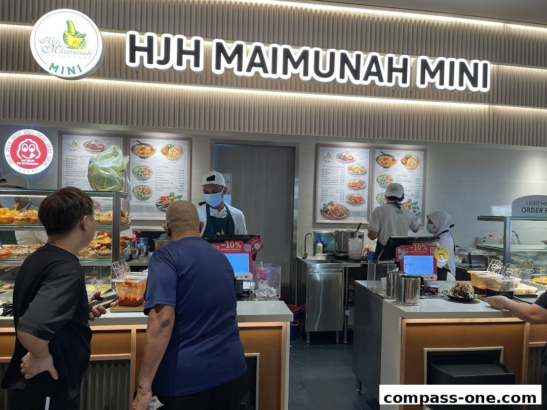 Customers ordering food at HJ H Maimunah Mini with menu boards displayed.