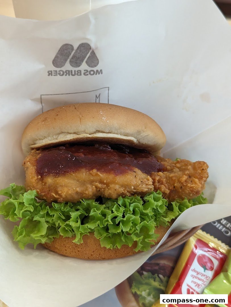 A delicious MOS Burger chicken sandwich with fresh lettuce and sauce.