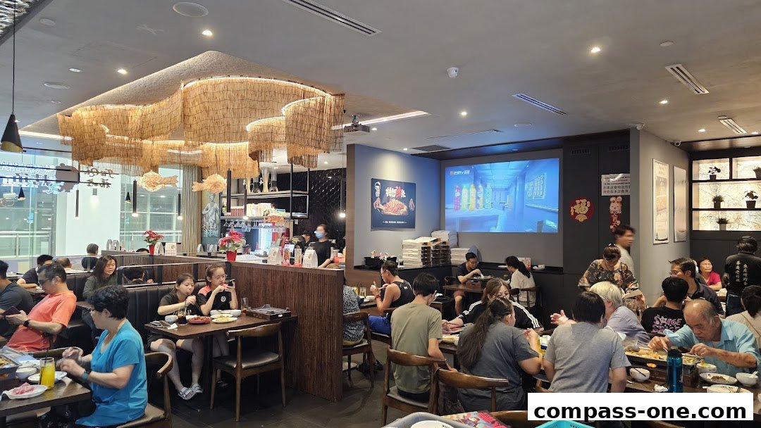 Diners enjoy grilled fish and other dishes in a modern restaurant with unique bamboo light fixtures.