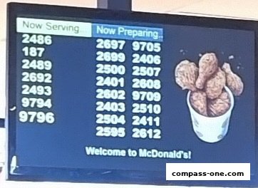 A digital screen at McDonald's displaying order numbers and an image of fried chicken.