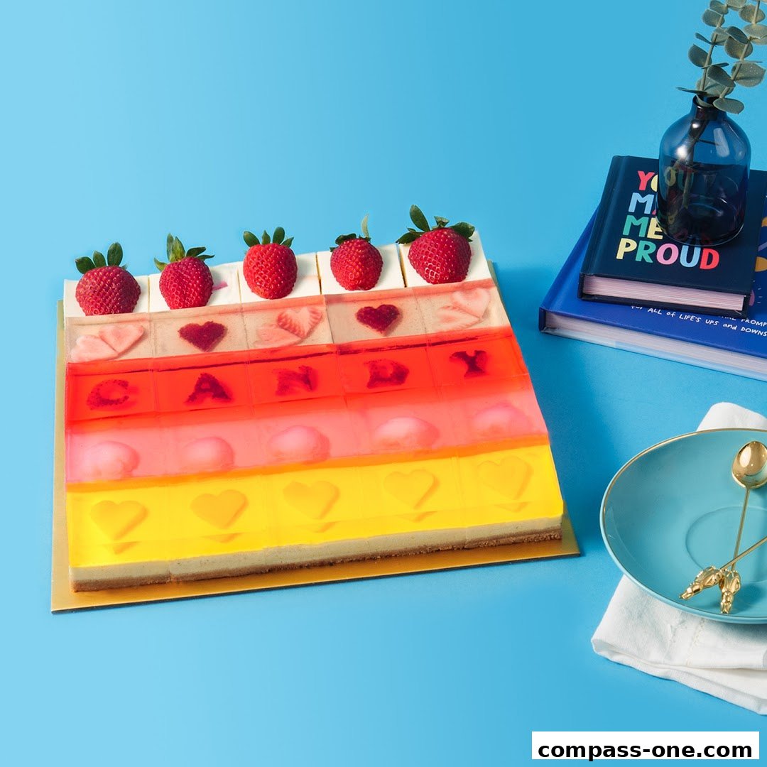 A colorful jelly cake with strawberries and heart shapes, presented on a blue background.