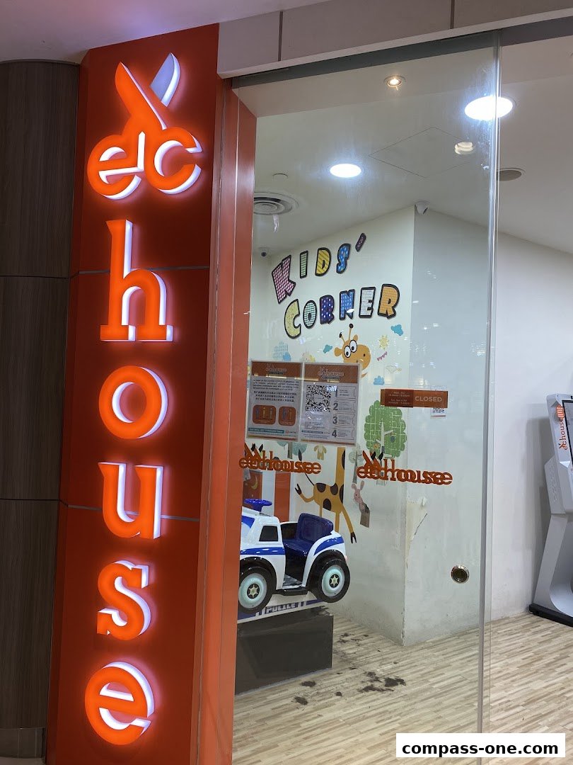 The illuminated sign of EC House All Range Cuts with a glimpse of a kids' play area inside.