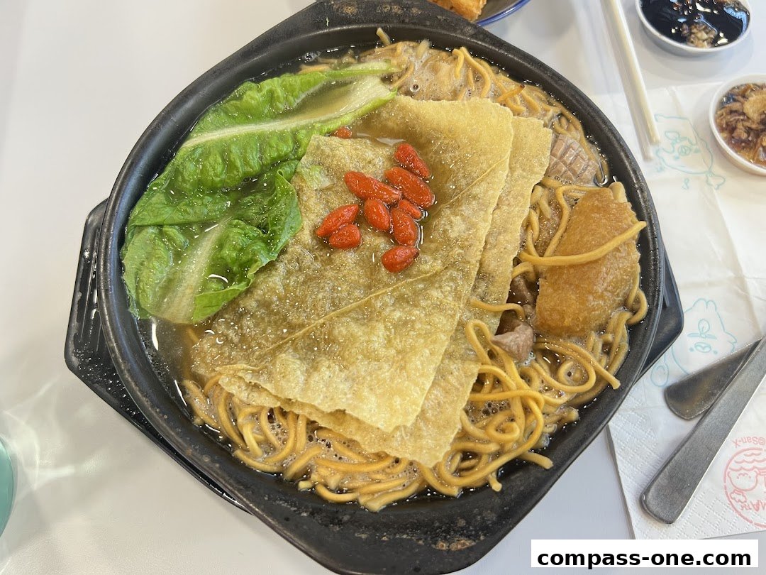 A steaming claypot of noodles with vegetables, tofu skin, and goji berries.