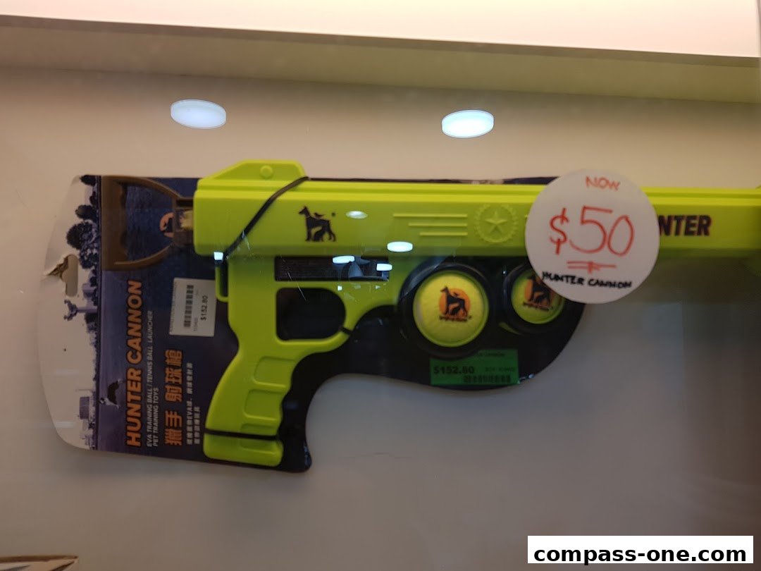 A bright yellow dog toy, a 'Hunter Cannon' ball launcher, is displayed with a price tag.