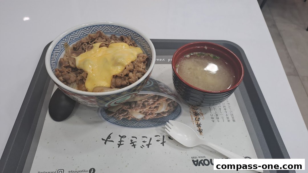 A Yoshinoya beef bowl with cheese and a side of miso soup on a tray.