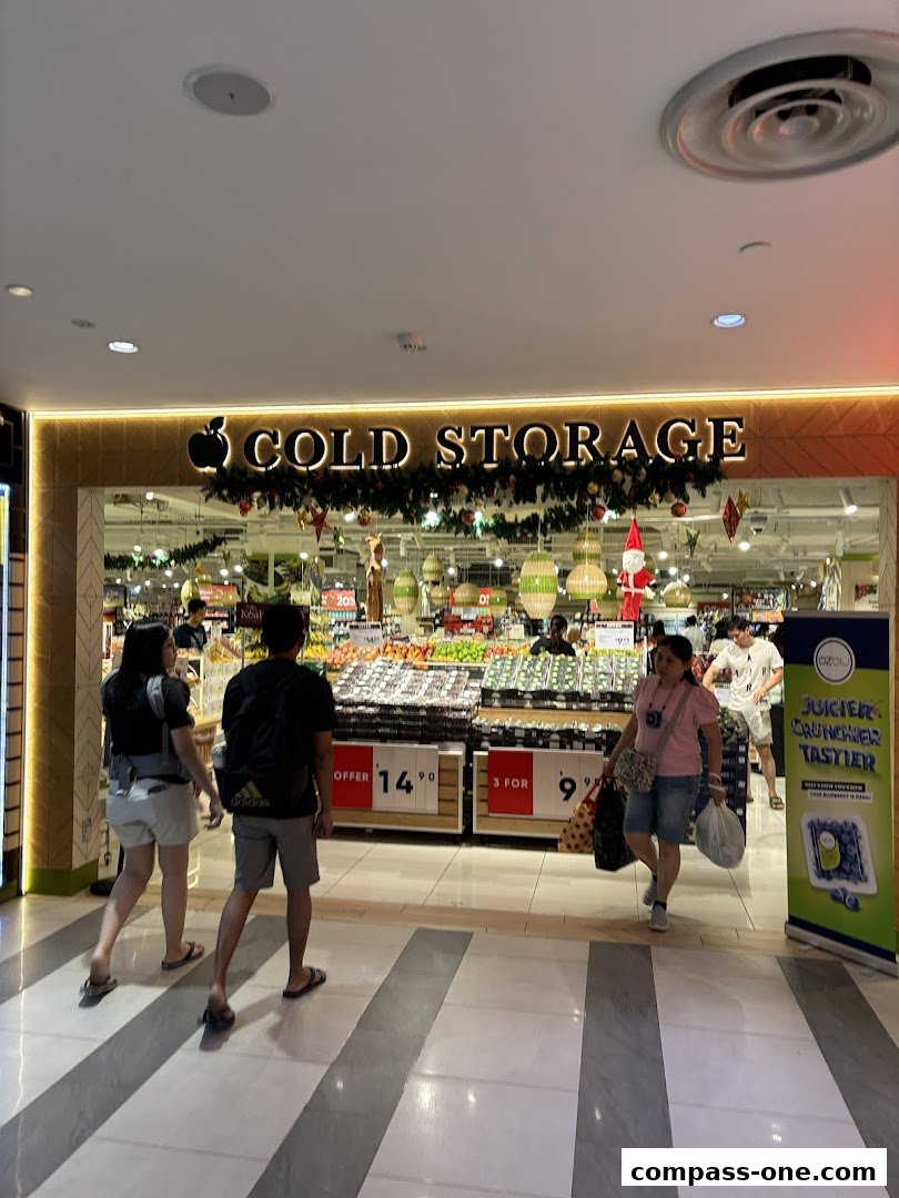 People walking into a Cold Storage supermarket with festive decorations and fruit displays.