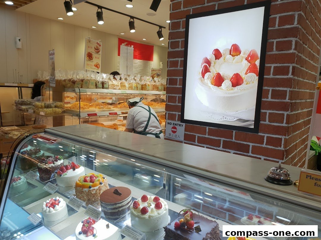 Interior view of a bakery with display cases filled with cakes and pastries.