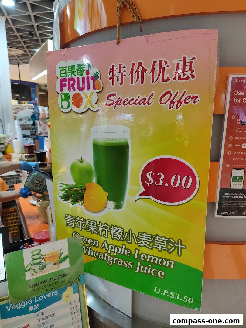 A sign advertising a special offer for Green Apple Lemon Wheatgrass Juice at Fruit Box.