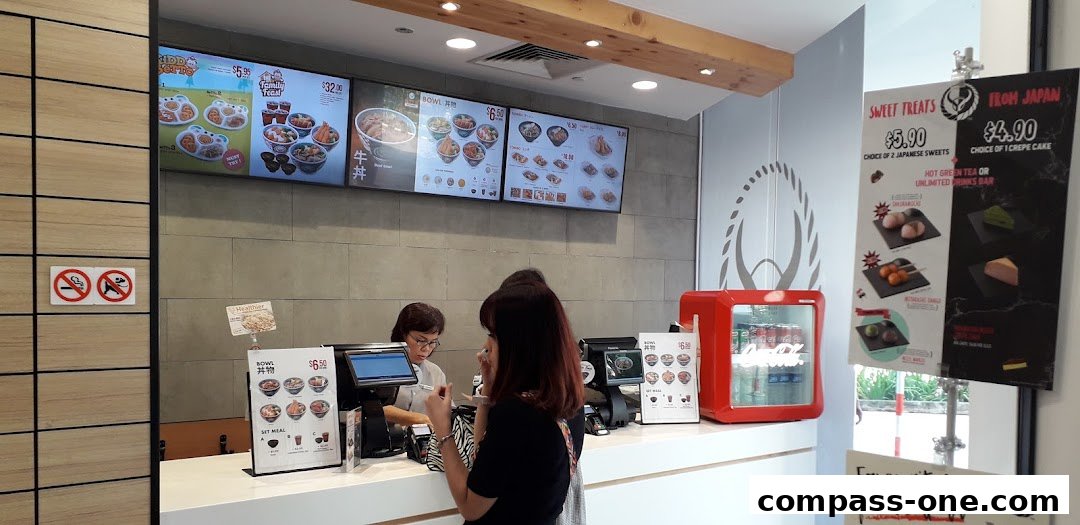 Yoshinoya counter with digital menus displaying food and drinks, and a red mini-fridge.