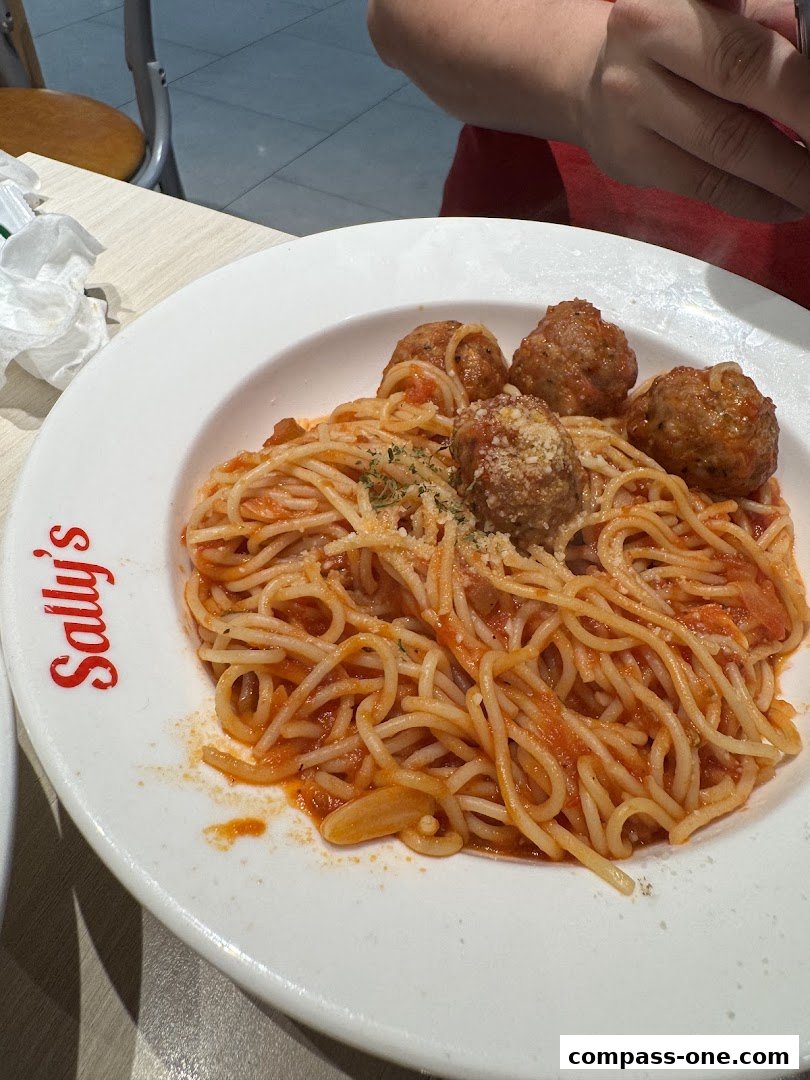 A plate of spaghetti with meatballs and tomato sauce, garnished with cheese.