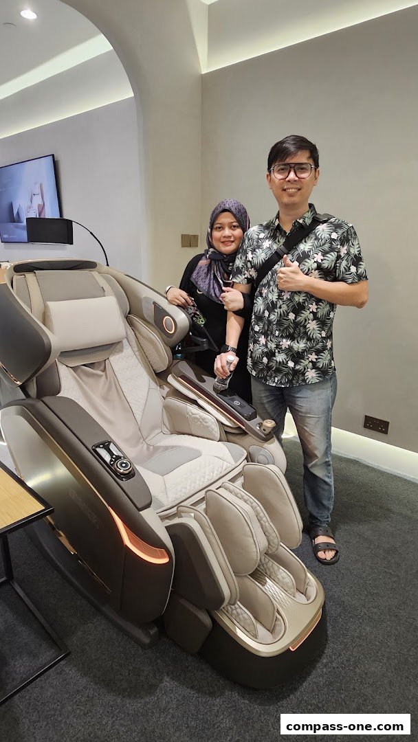 A couple poses with a luxurious massage chair in a modern retail store.