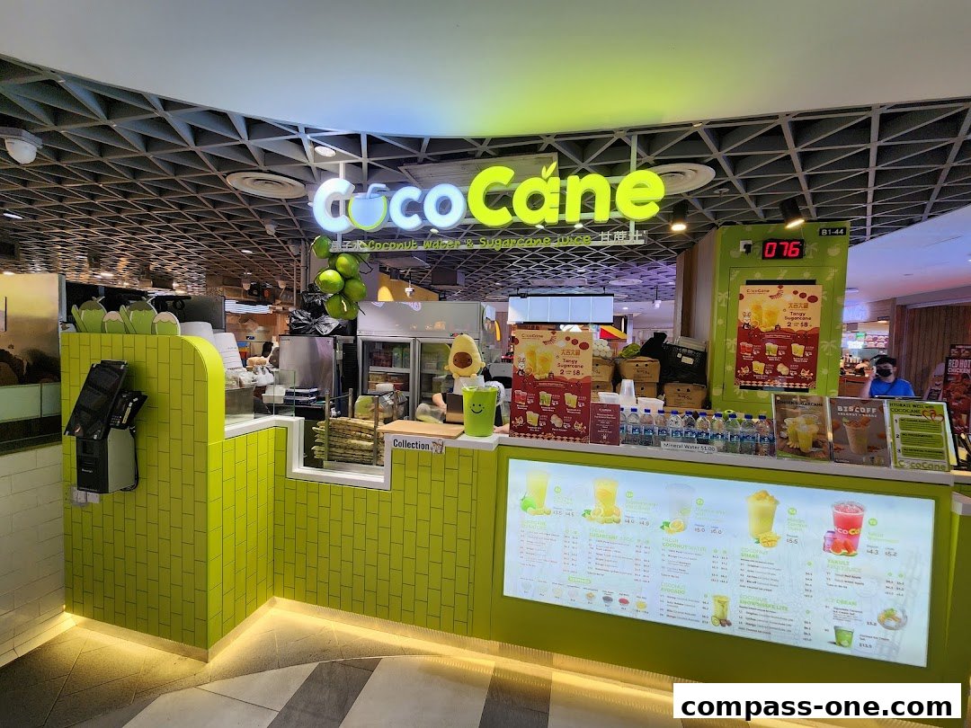 A brightly lit CocoCane shop counter with a menu display and sugarcane juice.
