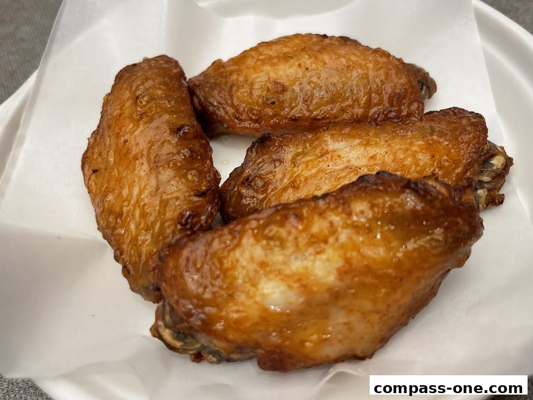 A close-up shot of several golden-brown, crispy chicken wings served in a white container.