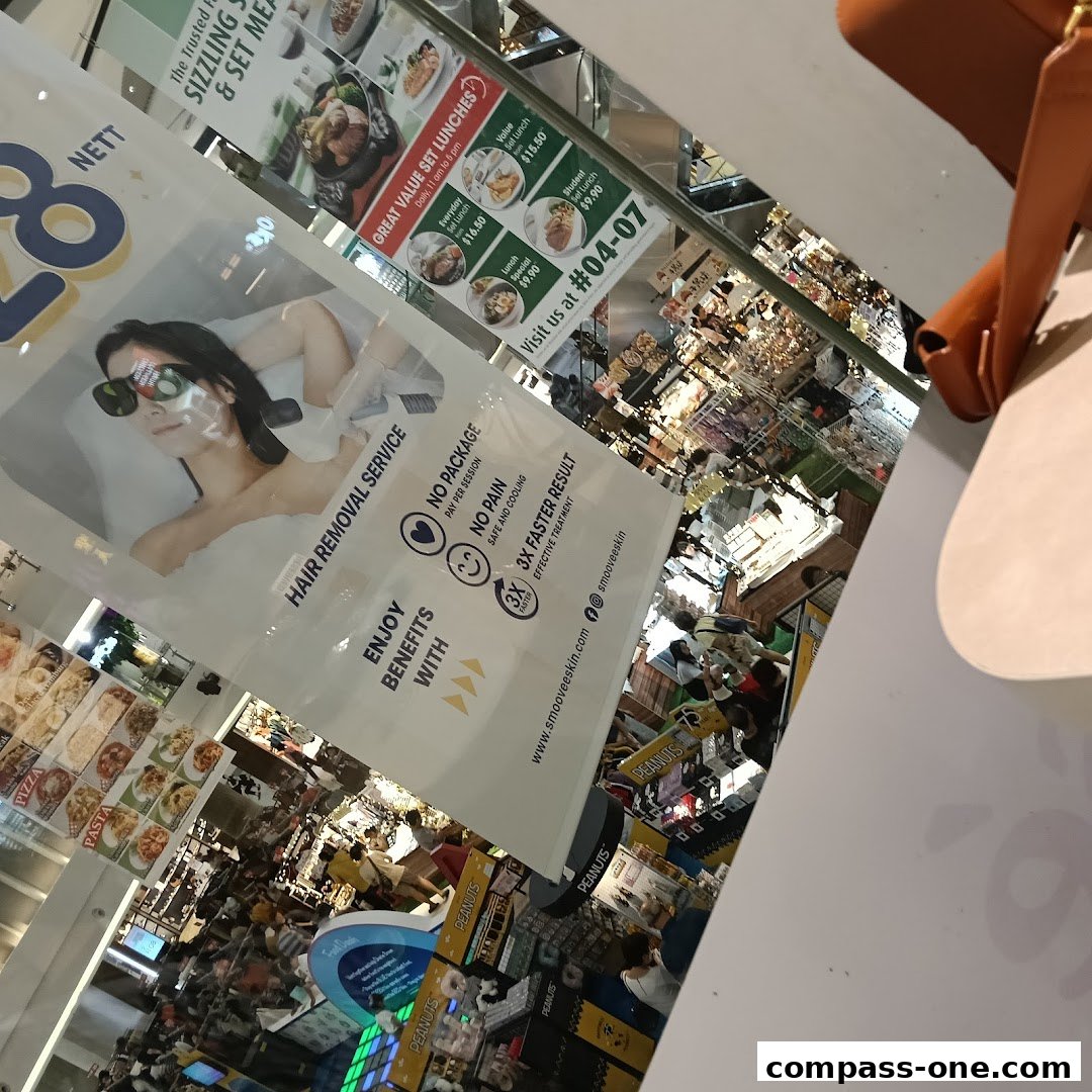A banner advertising hair removal services is displayed in a busy shopping mall.