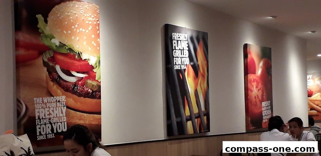 Burger King interior with posters of burgers, flame-grilled food, and tomatoes.