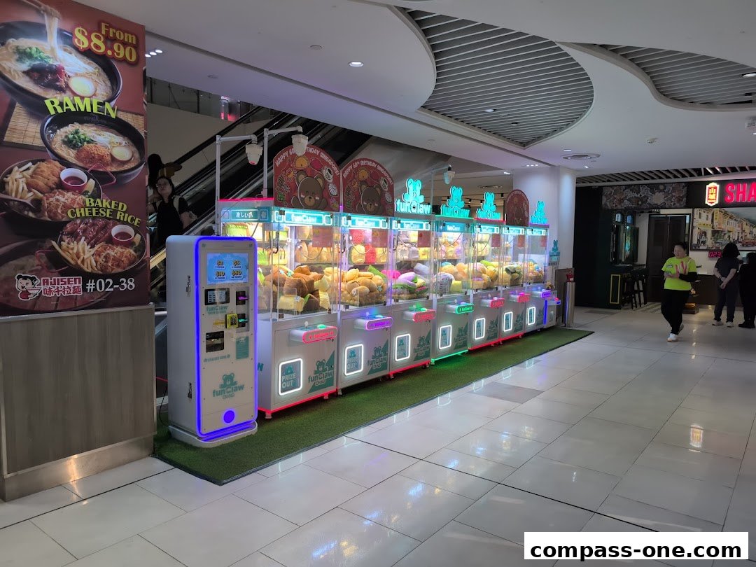 A row of colorful claw machines filled with plush toys in a shopping mall.