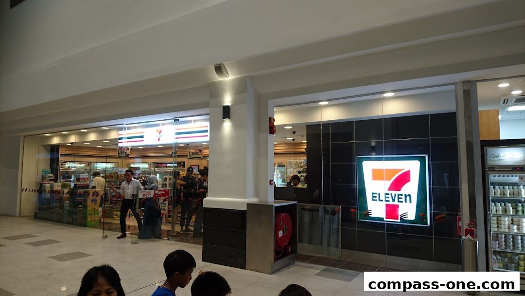 The exterior of a 7-Eleven convenience store with its iconic logo and bright interior.