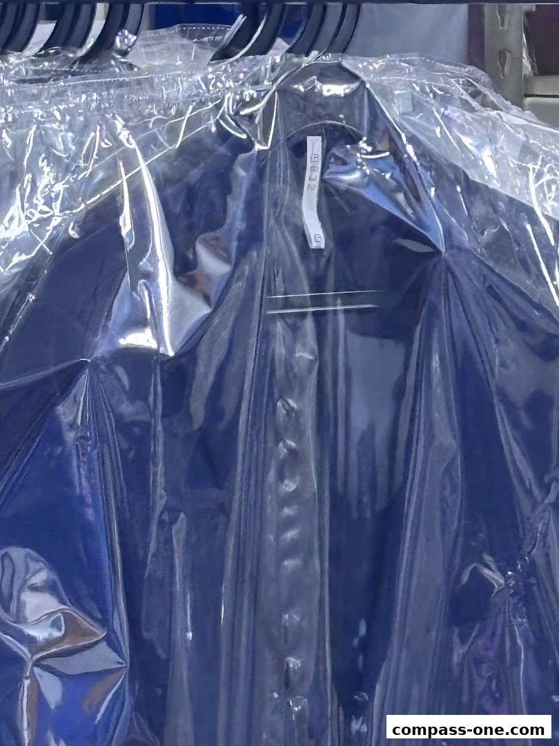 A dark blue shirt, neatly pressed and sealed in plastic, hanging on a rack.