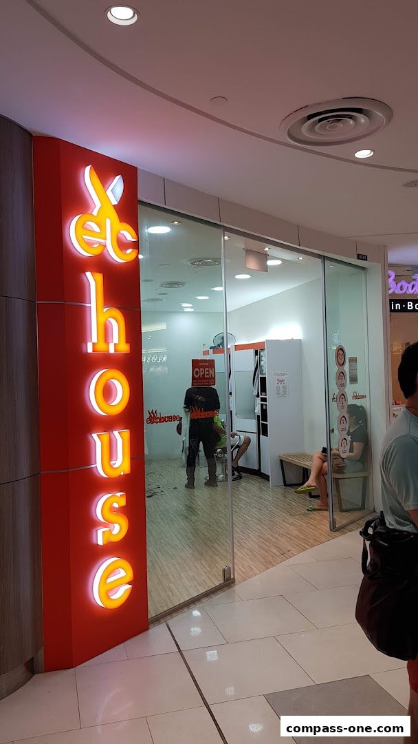 The entrance to EC House All Range Cuts, a hair salon, with illuminated signage and a glass door.