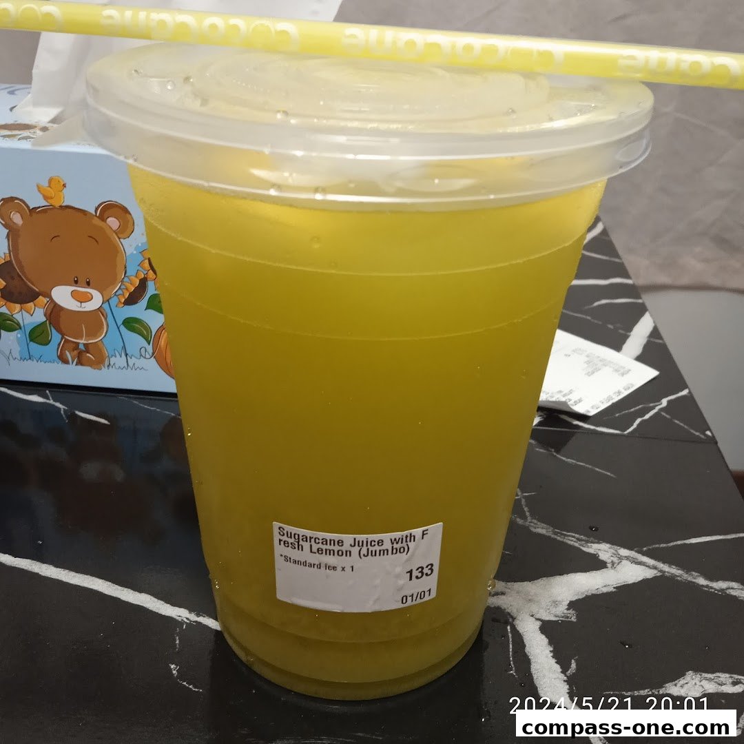 A jumbo cup of sugarcane juice with fresh lemon and a yellow straw.