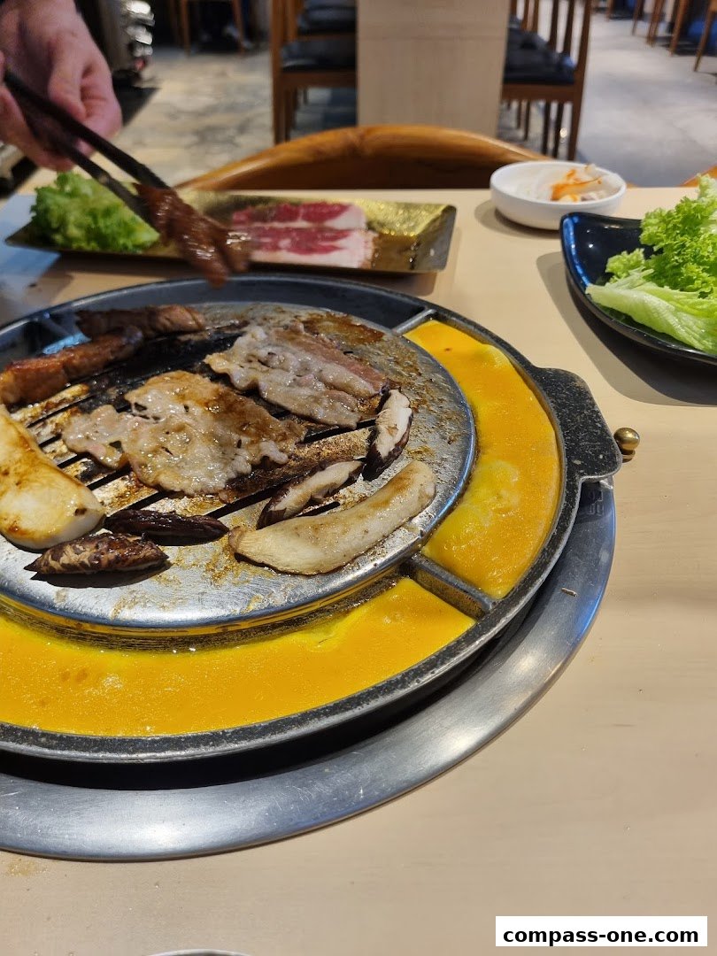 A close-up of Korean BBQ with meat and mushrooms being grilled on a circular grill.