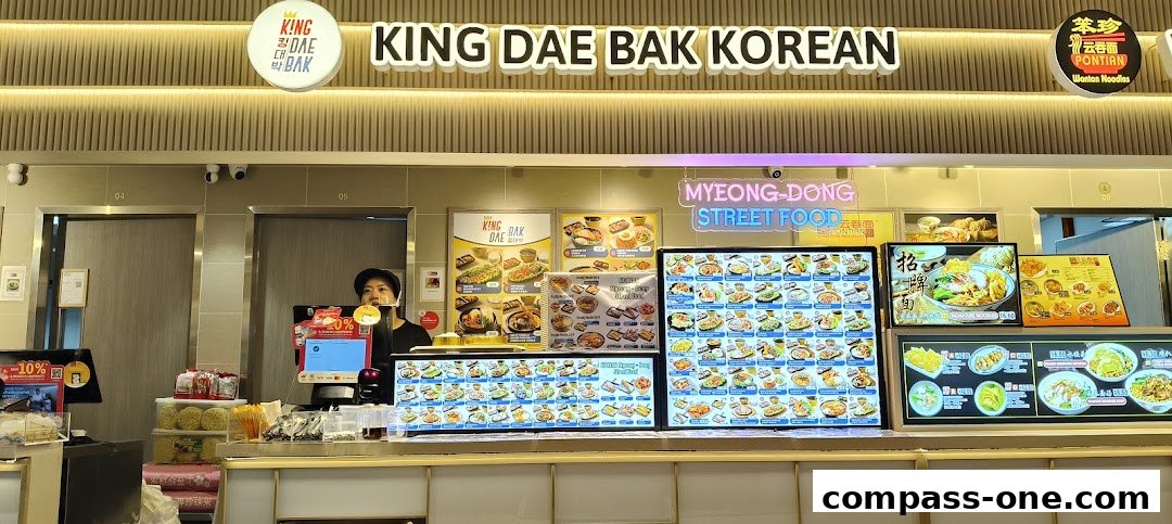 A view of the King Dae Bak Korean food stall with a staff member behind the counter.