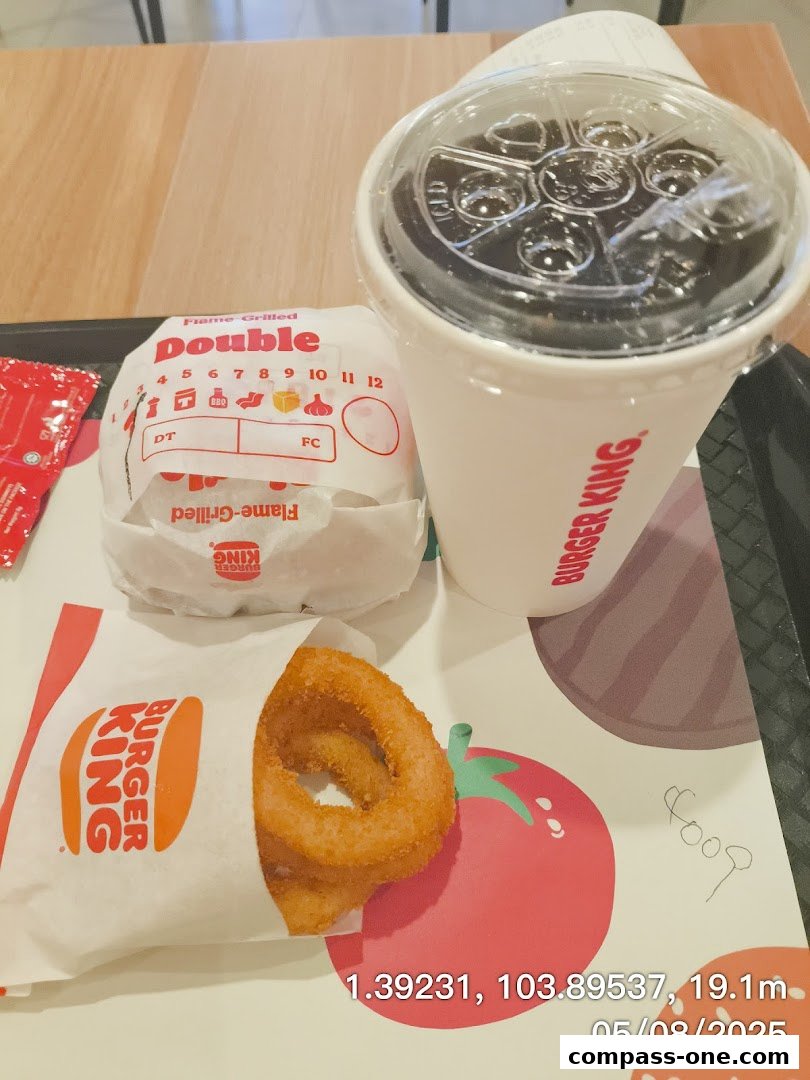 A Burger King meal featuring a double burger, onion rings, and a drink on a tray.