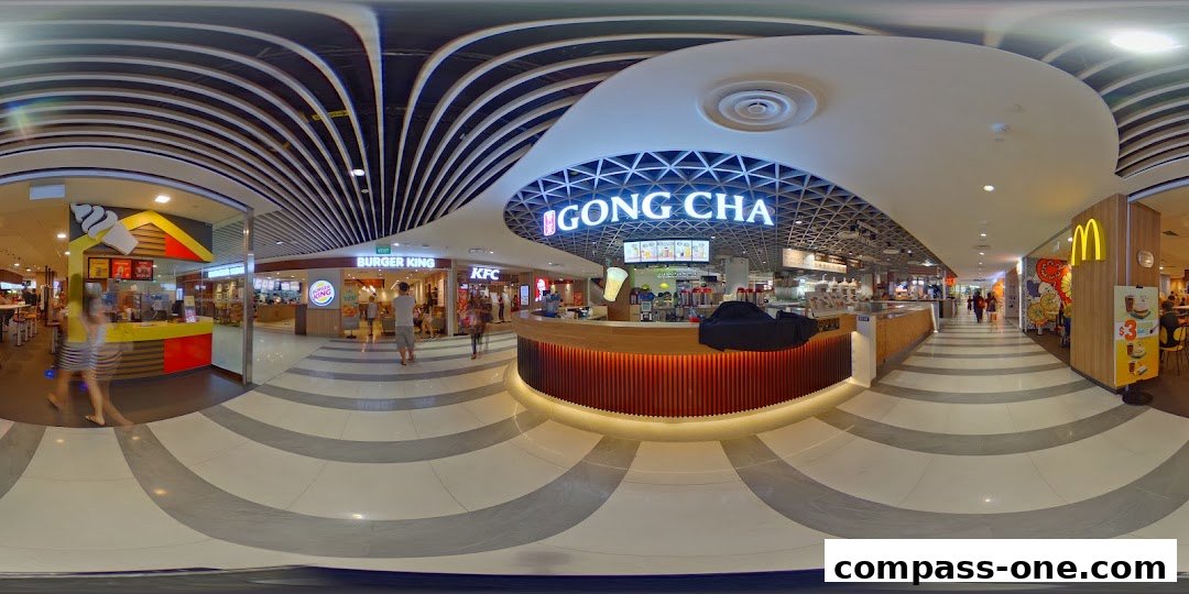 A wide shot of a bustling food court with various fast-food outlets including Gong Cha, Burger King, KFC, and McDonald's.