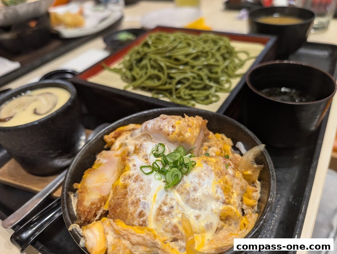 A close-up of a Japanese meal featuring katsudon, soba noodles, and chawanmushi.