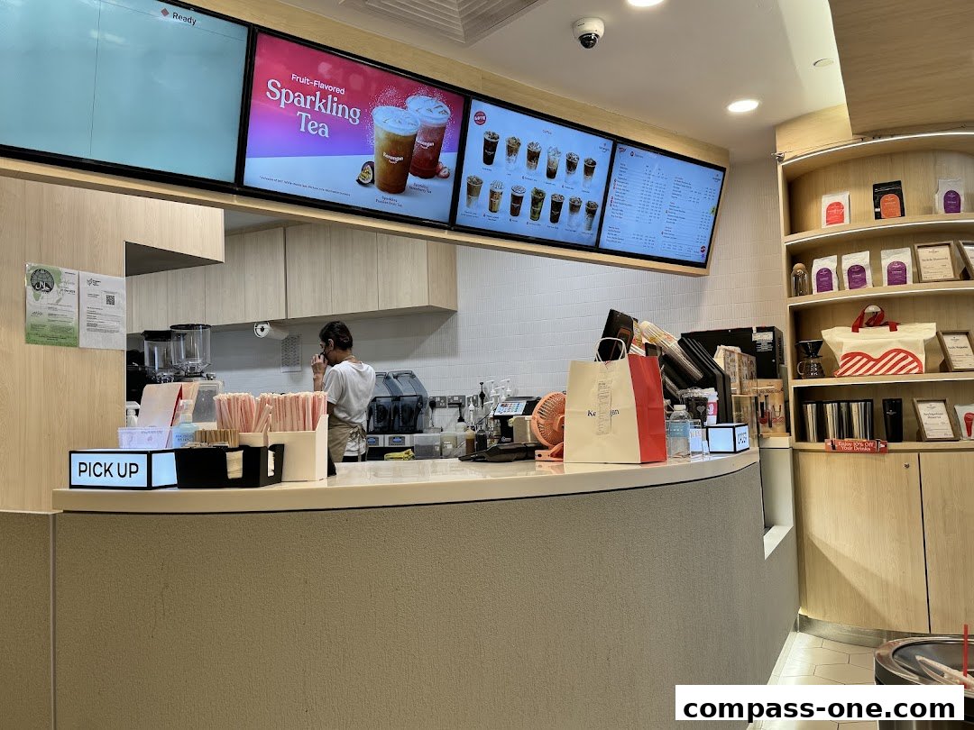 Interior view of Kenangan Coffee with a counter, staff, and digital menus displaying drinks.