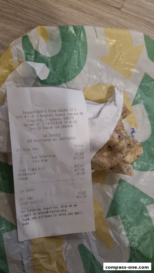 A receipt and a half-eaten wrap from Subway on branded packaging.