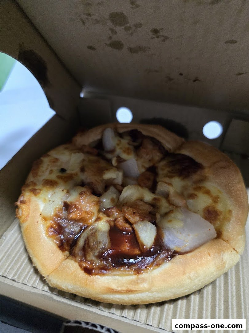A close-up of a delicious pizza with cheese, chicken, and sauce in a cardboard box.