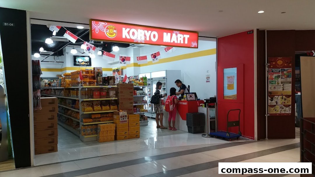 Koryo Mart shop entrance with shelves stocked with products and customers at the counter.