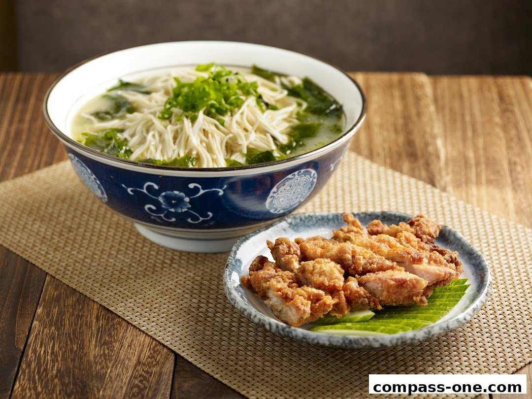 A bowl of noodles with seaweed and a plate of crispy fried chicken.