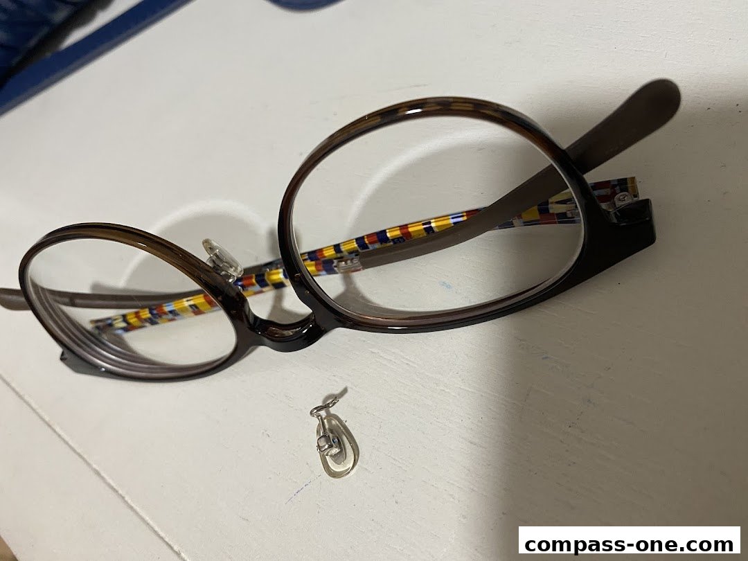 A pair of brown-rimmed glasses with colorful striped temples and a detached nose pad.