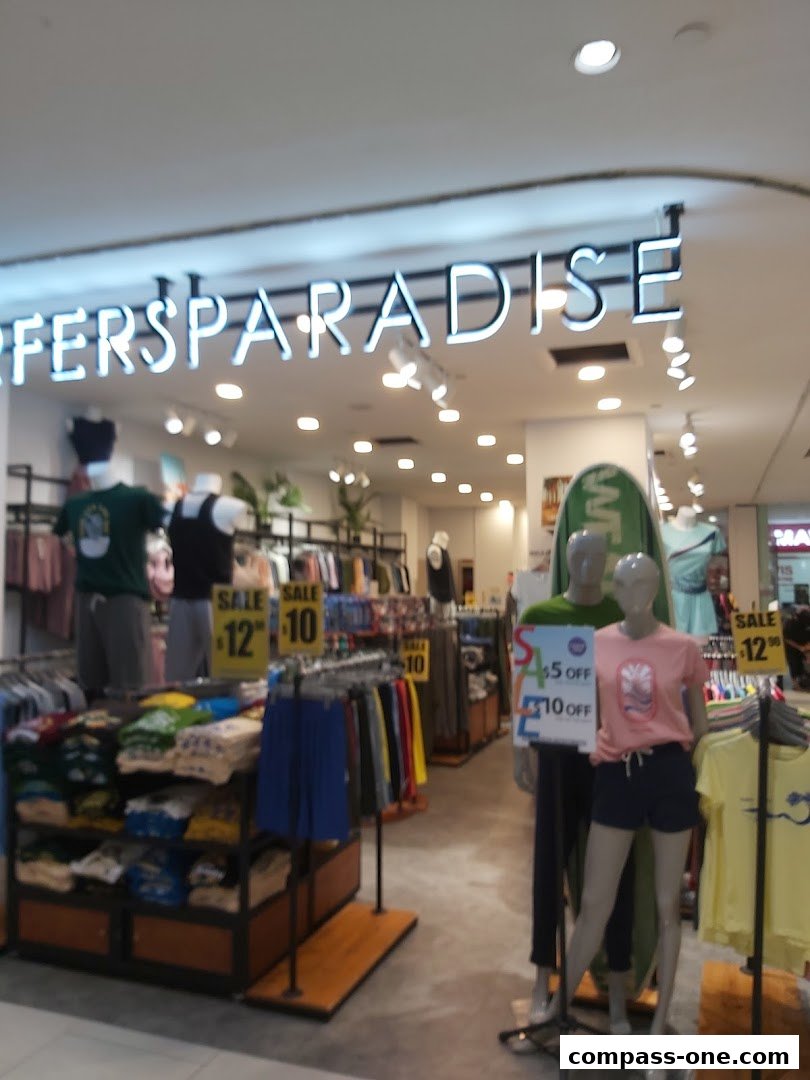 The Surfers Paradise shop interior displays clothing on racks and shelves, with mannequins showcasing outfits.