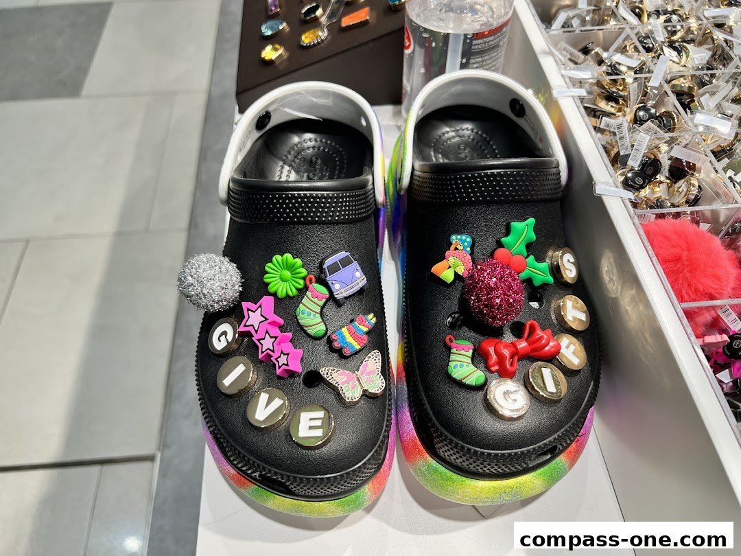 Black Crocs decorated with colorful Jibbitz charms, including holiday-themed and letter charms.