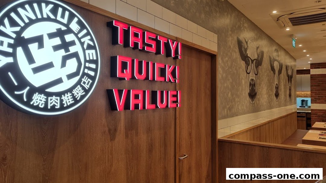 Interior shot of Yakiniku Like Compass One with neon signs and cow artwork.