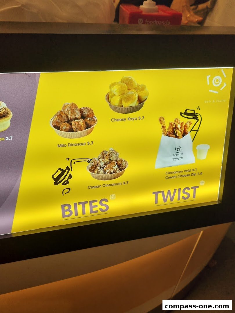 A brightly lit menu board showcasing various sweet and savory pastry bites with prices.