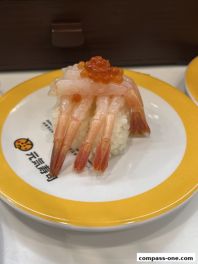 A plate of sushi with shrimp and roe on a conveyor belt.