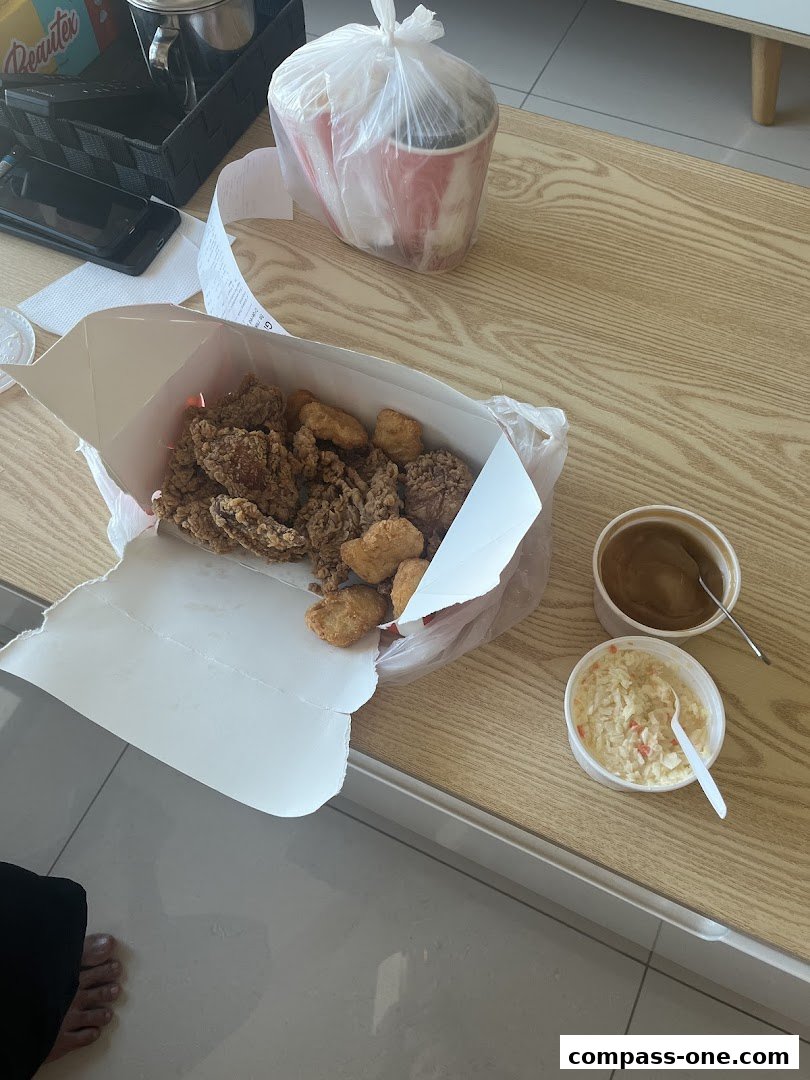 A box of KFC fried chicken and sides on a wooden table.