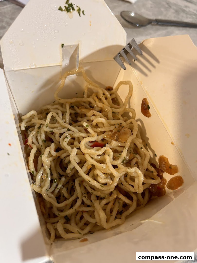 A close-up of freshly made pasta in a takeaway box with a fork.