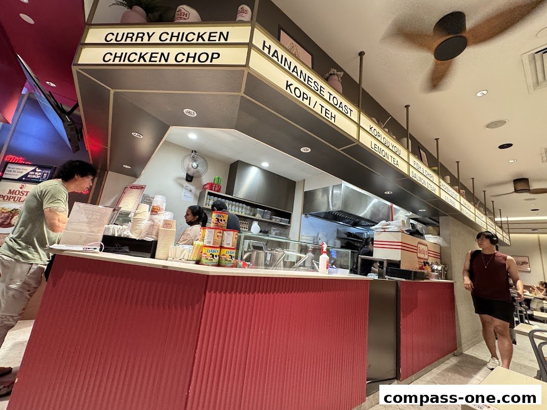 Customers ordering food at a counter with a menu board above.