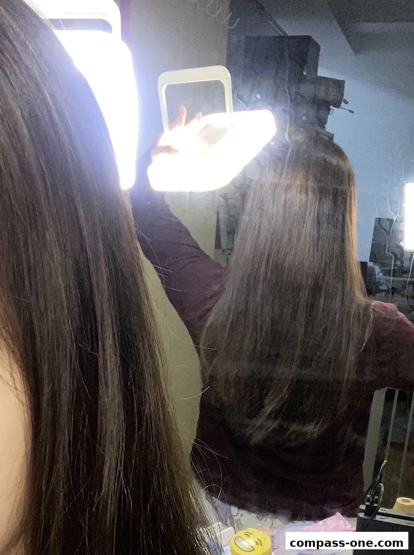 A person is holding a portable ring light in front of a mirror, reflecting their hair.