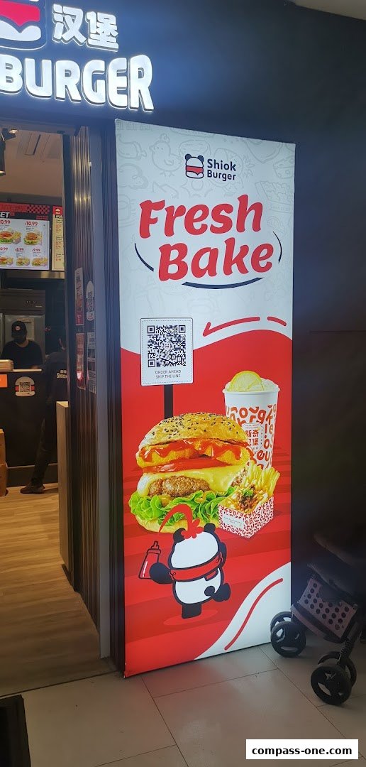The entrance of Shiok Burger with a large banner showcasing a burger, fries, and a drink.
