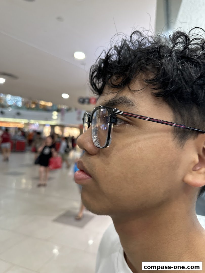 A close-up profile shot of a person wearing glasses in a shopping mall.