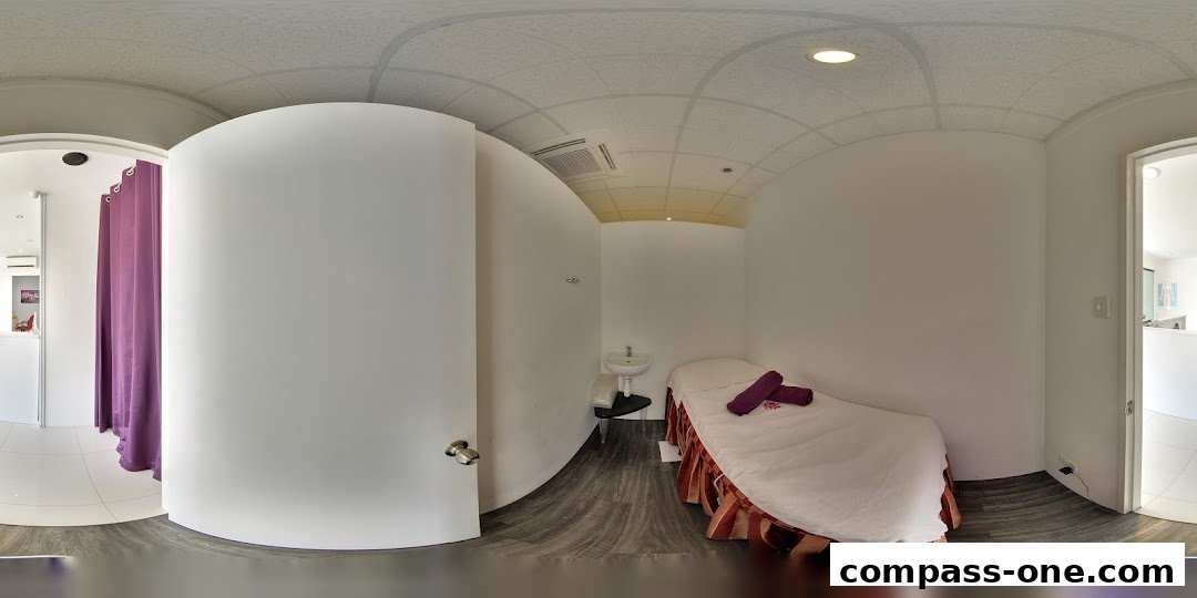 Interior view of a clean and modern spa treatment room with a massage bed and sink.